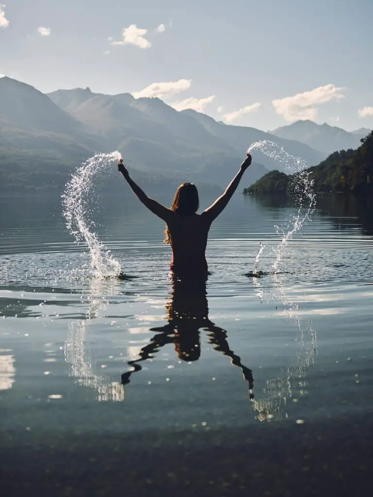 woman raising her two hands with splashing water