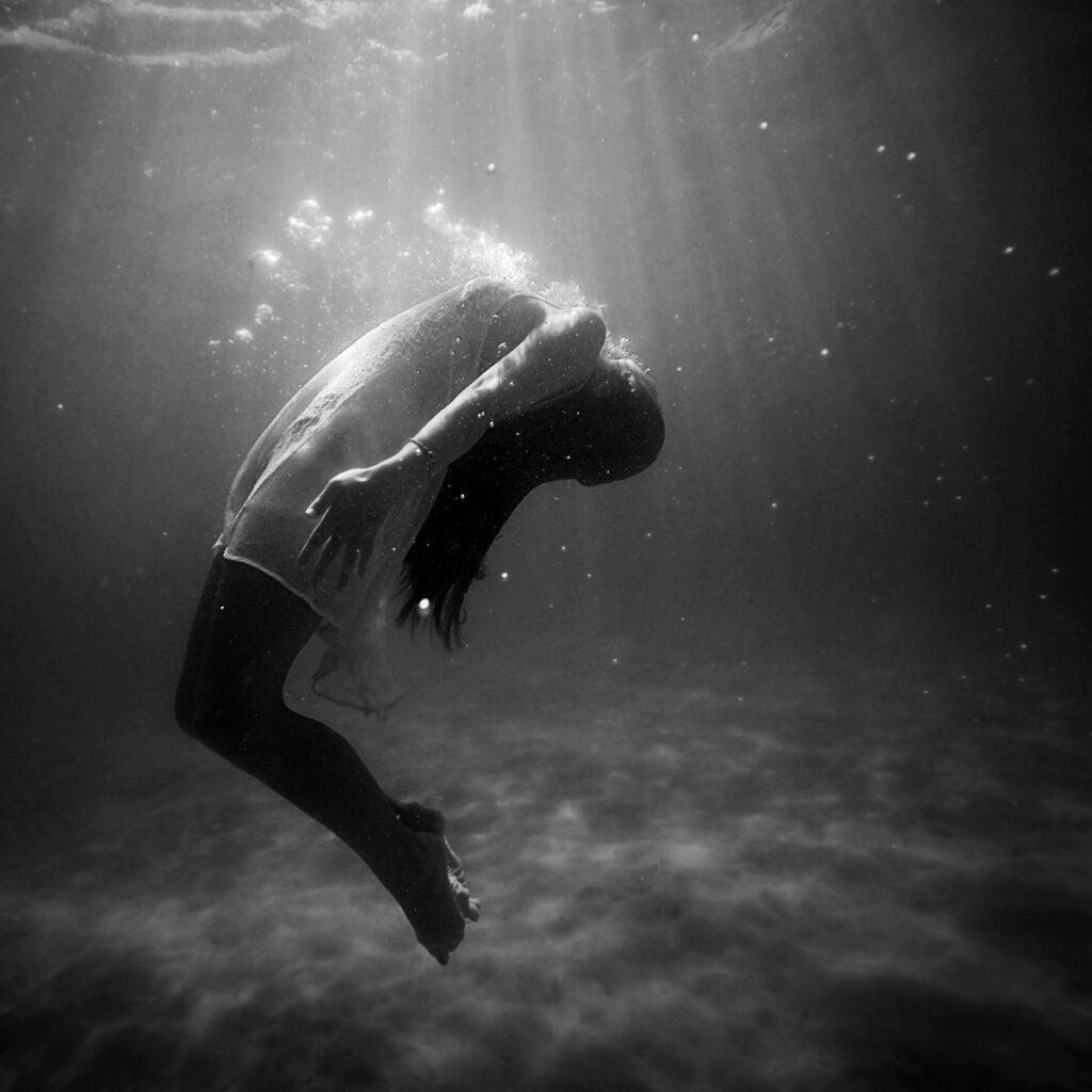 grayscale photo of woman drowning in water sinking dream