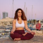meditating woman in white sports bra and red yoga pants outfit