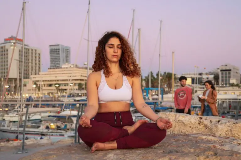 meditating woman in white sports bra and red yoga pants outfit