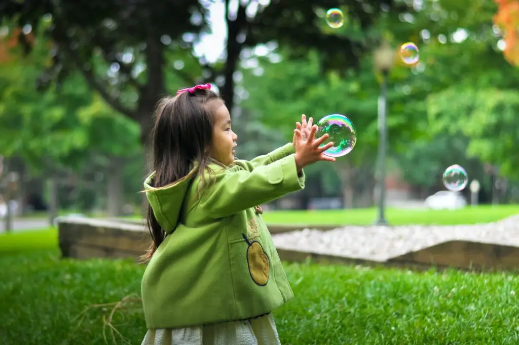 selective photo of a girl holding bubbles child dream