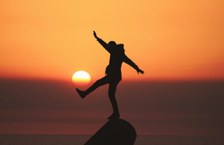 photo of silhouette photo of man standing on rock life